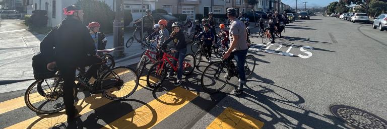 Group of children and several adults biking to school together